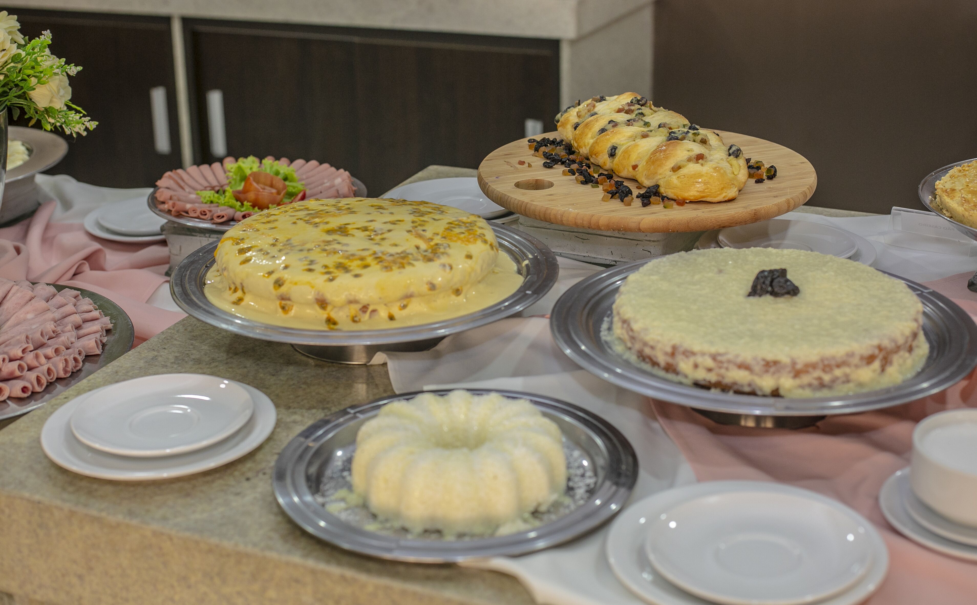 A buffet table with various dishes, including a cake with a chocolate decoration, a dish with a yellow sauce, and a dish with a green topping.