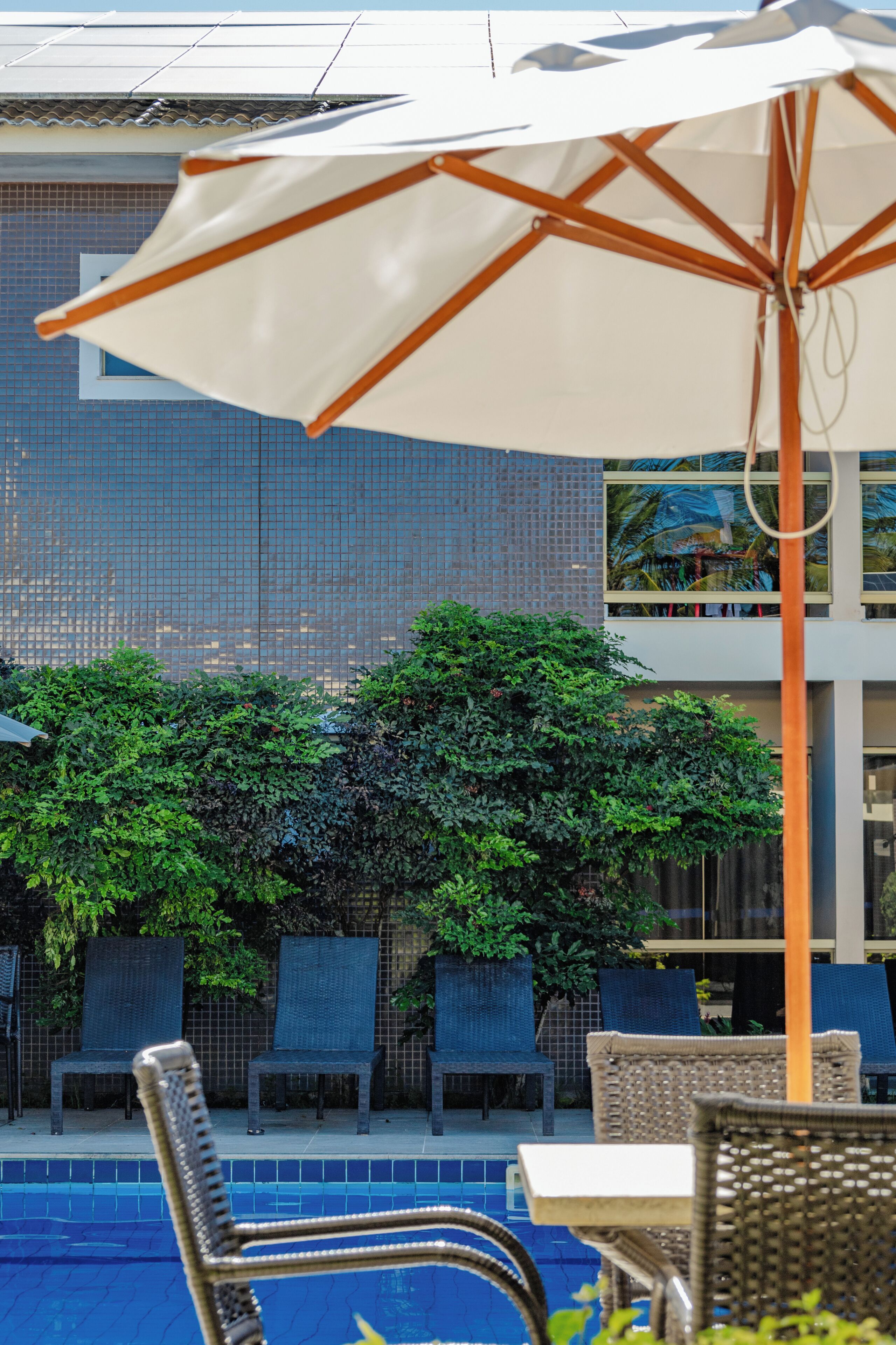 A pool area with lounge chairs and an umbrella.