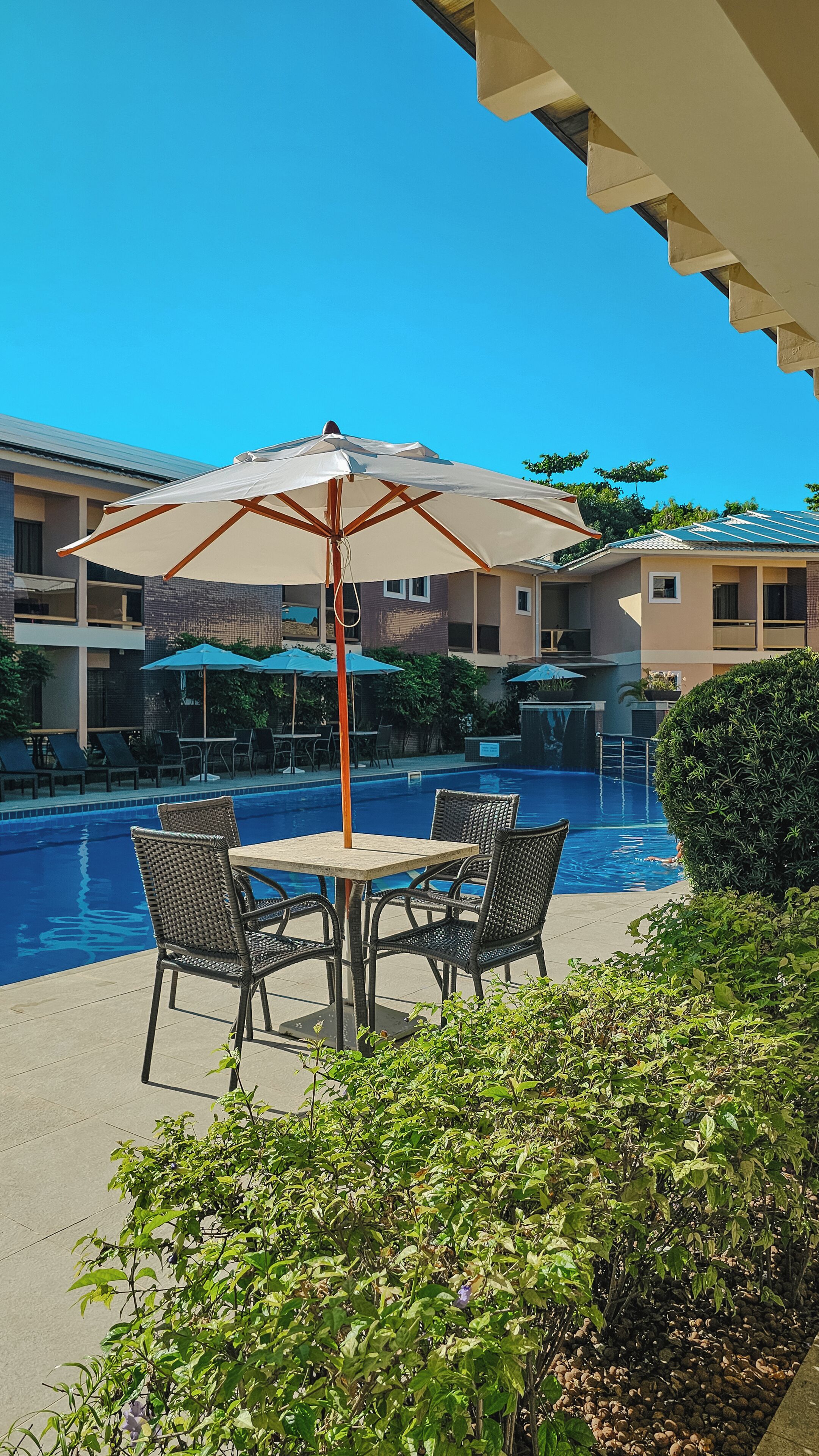 Área de piscina com mesa, cadeiras e guarda-sol.