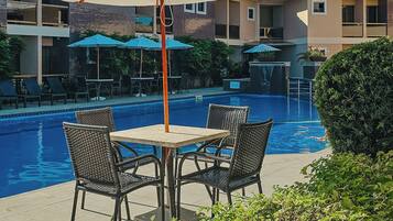 Área de piscina com mesa, cadeiras e guarda-sol.