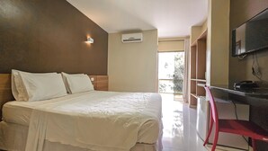 A hotel room with a bed, a desk, a chair, an air conditioning unit, and a TV mounted on the wall. - Safira Praia Hotel (Porto Seguro)
