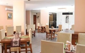 Un espace de restauration d’hôtel comprenant plusieurs tables et chaises, des unités de climatisation et une cloison vitrée.