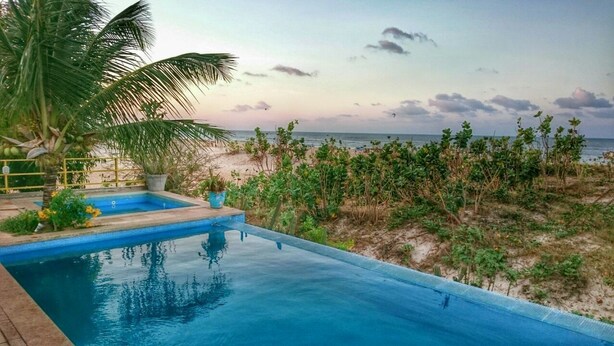 Ein Schwimmbecken mit Blick auf Strand und Meer.