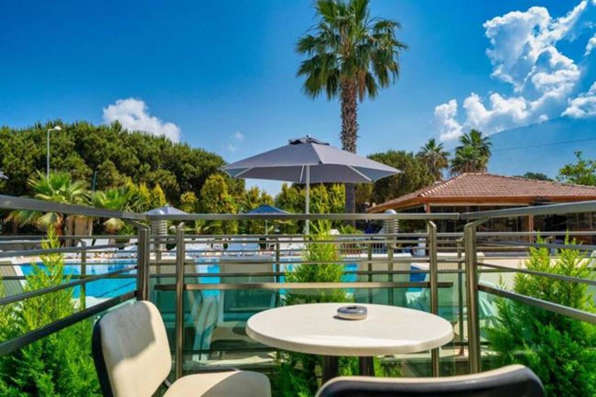 A poolside area with a glass balustrade, a round table, and a grey umbrella.