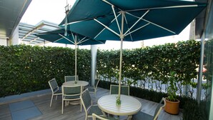 An outdoor patio with round tables and chairs, umbrellas, and a potted plant. - Hotel Atenas Plaza (Mexico City)