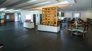 A spacious lobby with a reception desk, a wooden partition with plants, and a seating area with tables and chairs. - Hotel Atenas Plaza (Mexico City)