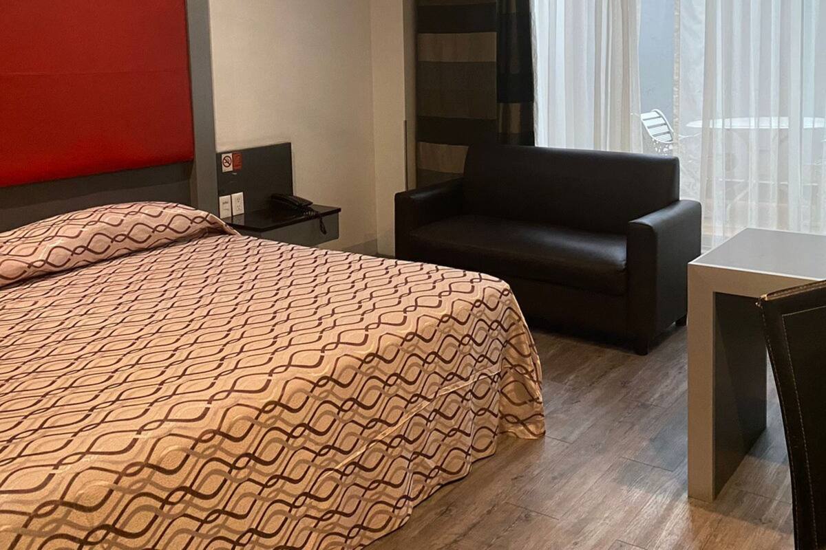 Une chambre d’hôtel moderne avec un grand lit, un canapé, une petite table et un ventilateur de plafond.