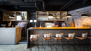 Un área de bar moderna con estantes de madera, taburetes y luces colgantes.
