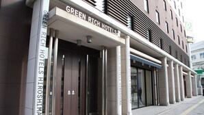 The exterior of the Green Rich Hotels Hiroshima building with a modern facade, large glass windows, and a prominent entrance with a dark wooden door. - Green Rich Hotel Hiroshima Shinkansenguchi (Artificial hot spring Futamata Yunohana) (Hiroshima)