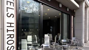 A hotel entrance with glass doors, outdoor seating with metal chairs, and a sign reading "HIROSHIMA". - Green Rich Hotel Hiroshima Shinkansenguchi (Artificial hot spring Futamata Yunohana) (Hiroshima)