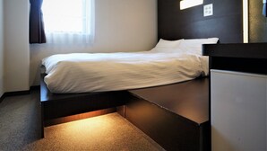A modern hotel room with a bed, a bedside table, a small desk, and a window with curtains. - Green Rich Hotel Hiroshima Shinkansenguchi (Artificial hot spring Futamata Yunohana) (Hiroshima)