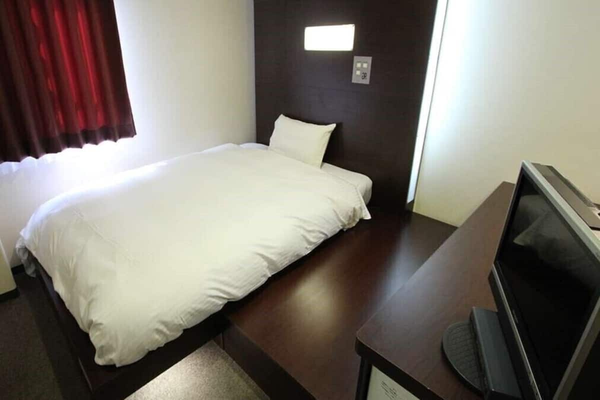 Een hotelkamer met een bed, een televisie en een klein bureau.