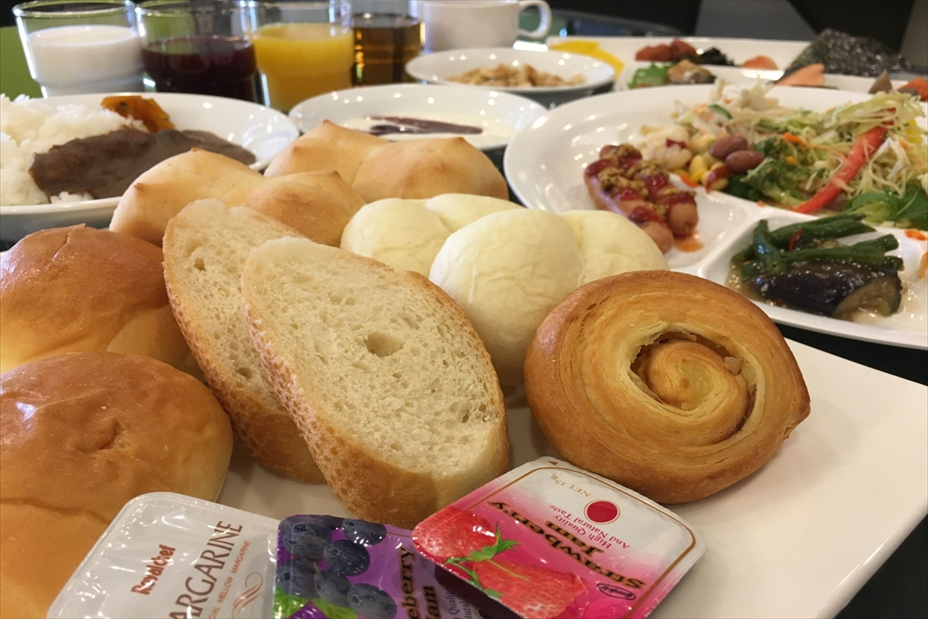 Una mesa con diversos panes, pasteles y un pequeño recipiente de yogur.