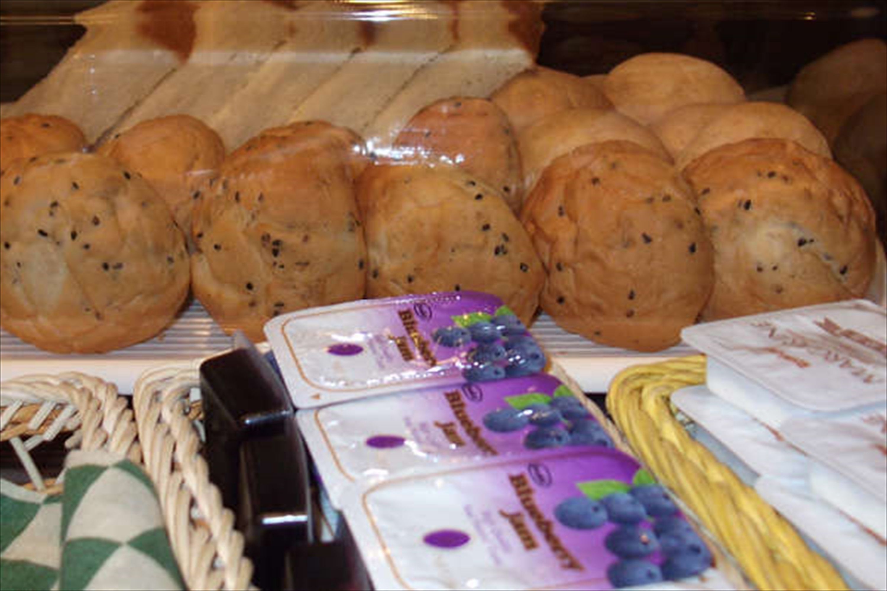 A bakery display with various types of bread and packaged pastries.