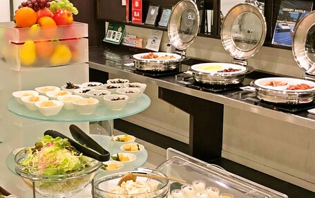 A buffet with various food options including fruits, salads, and desserts.