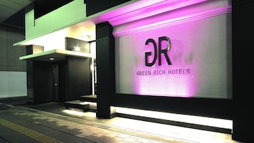 A modern hotel entrance with a prominent illuminated sign reading "GREEN RICH HOTELS".