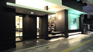 A modern hotel entrance with a glass door, a reception desk, and a sign indicating it is the Green Rich Hotel.