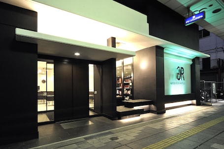 A modern hotel entrance with a glass door, a reception desk, and a sign indicating it is the Green Rich Hotel.