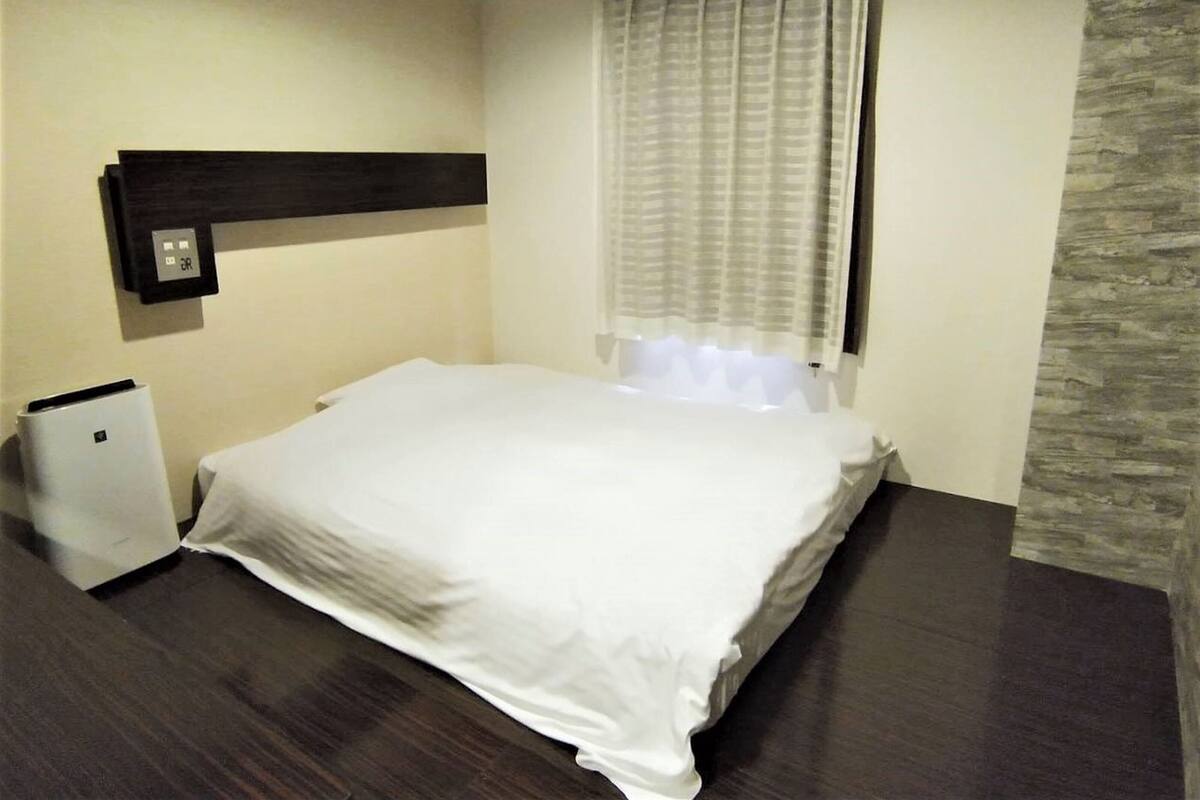Une chambre d’hôtel avec un lit, un radiateur et une fenêtre avec des rideaux.