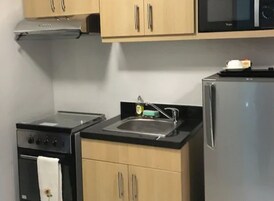 Una cocina compacta con estufa, pileta y microondas.