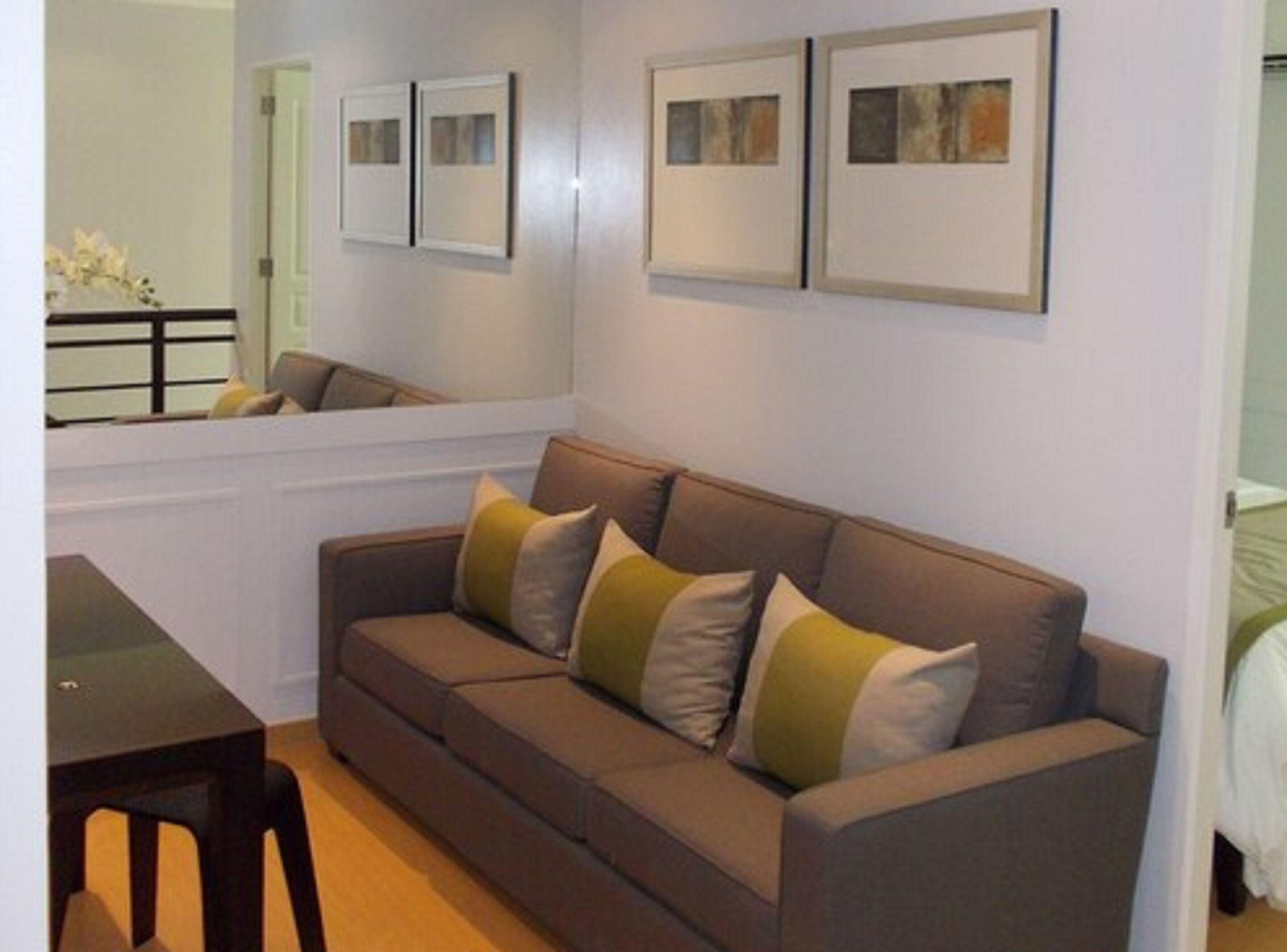 A modern living room with a brown sofa, a small table, and framed artwork on the wall.