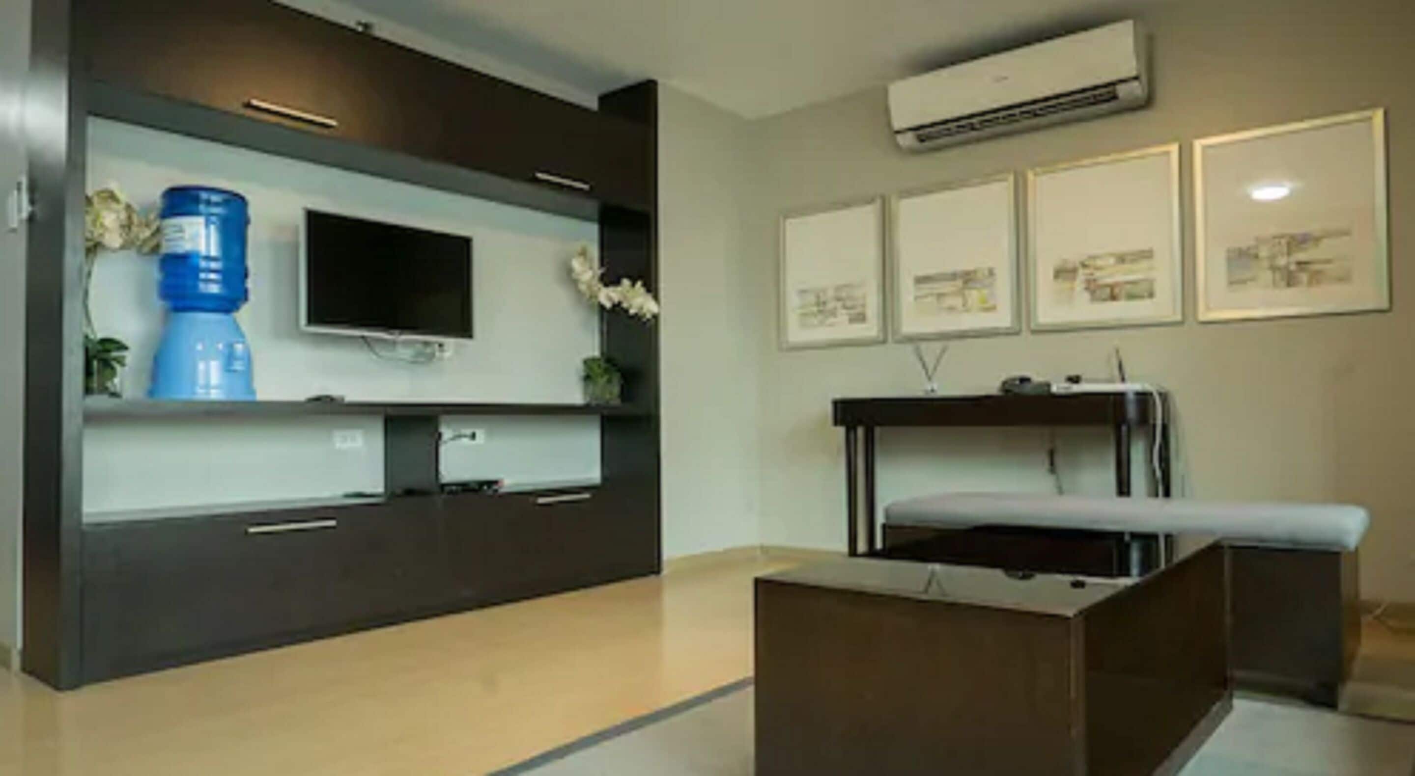 Una habitación moderna con televisión de pantalla plana, dispensador de agua y una cama con cabecera.