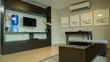Una habitación moderna con televisión de pantalla plana, dispensador de agua y una cama con cabecera.