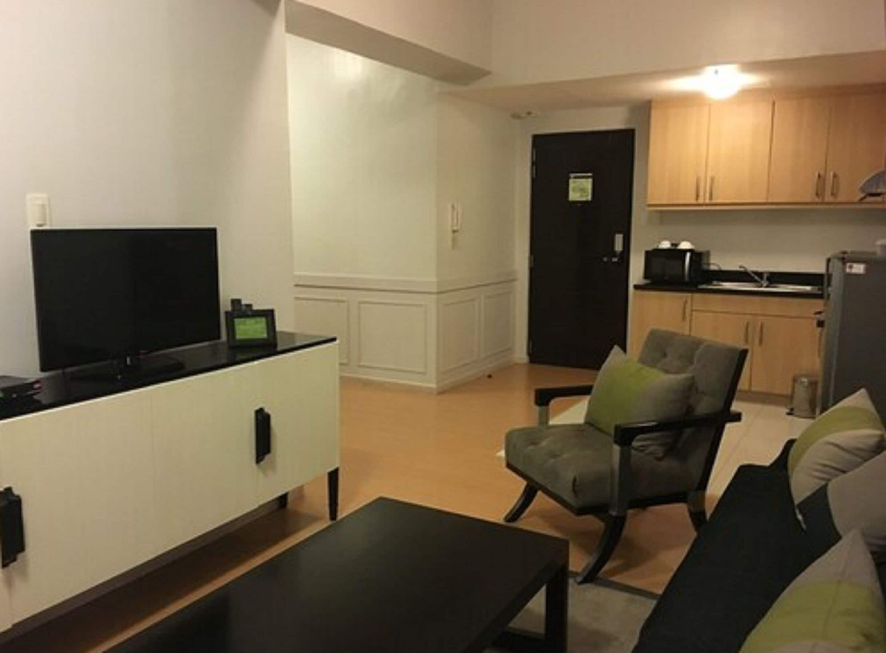 A compact living space with a kitchenette, a flat-screen TV, a dining table, and a comfortable seating area.