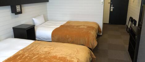 Une chambre d’hôtel avec deux lits, une petite table de chevet, une armoire et une porte dotée d’un porte-manteau.