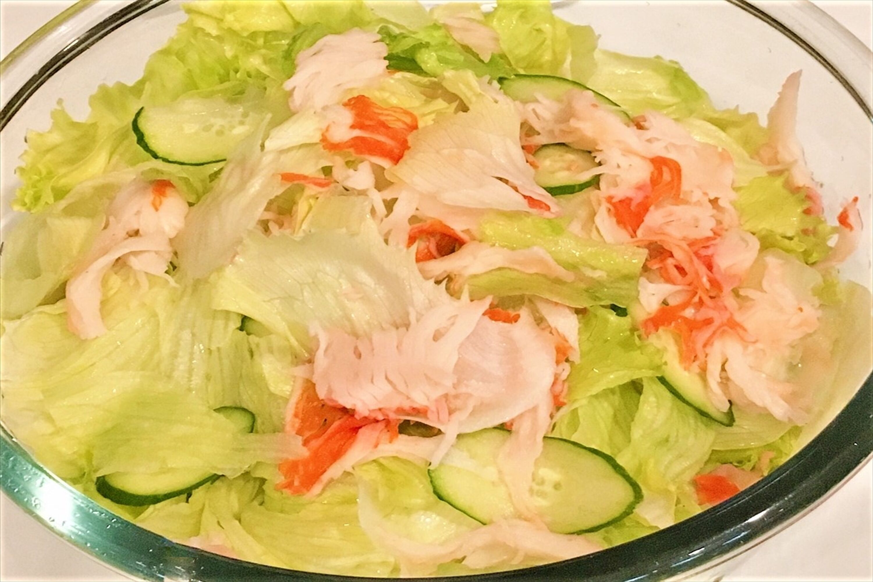 Une salade composée de laitue, de concombre et de carottes râpées.