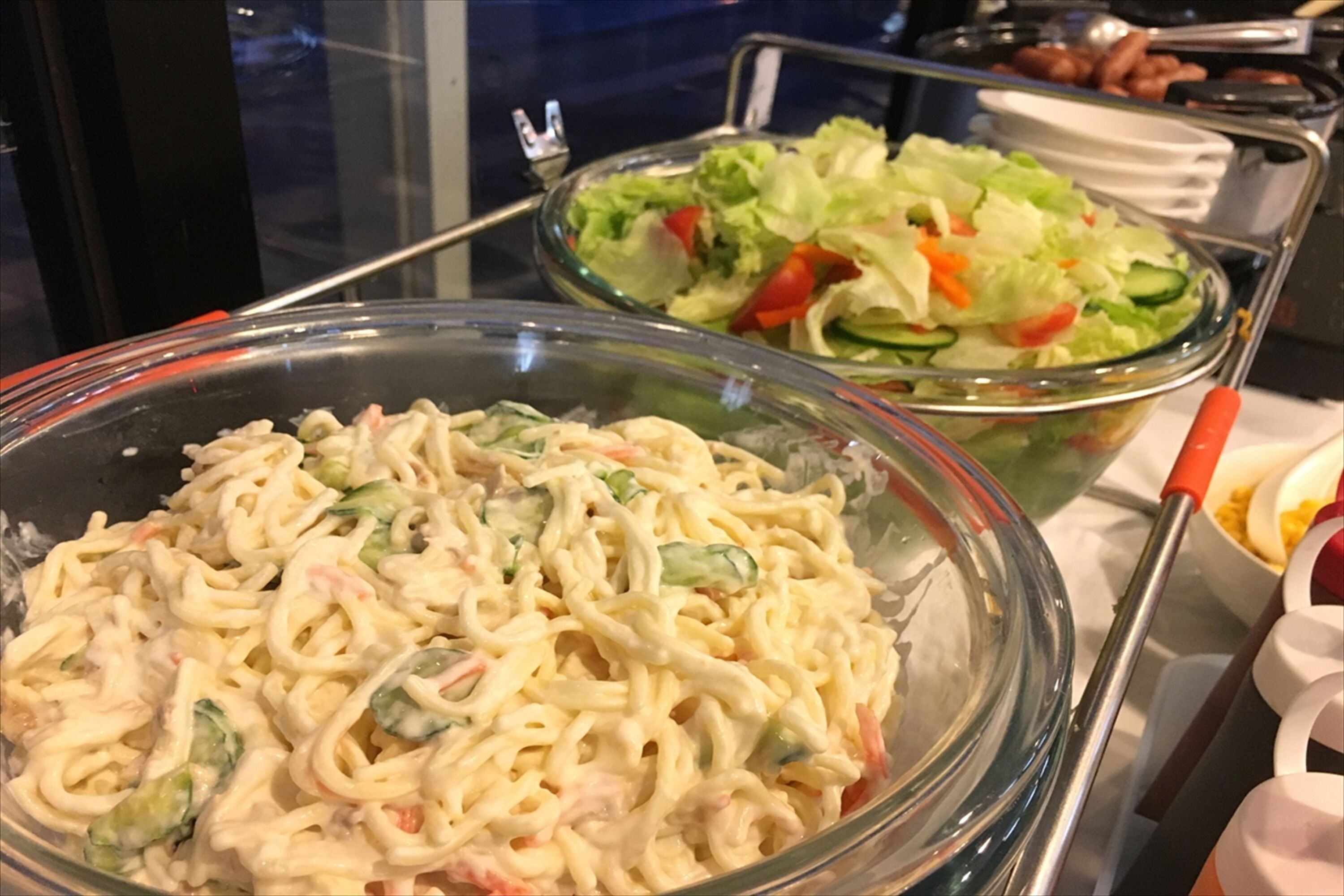 Een buffet met pastasalade, een salade met groenten en andere gerechten.