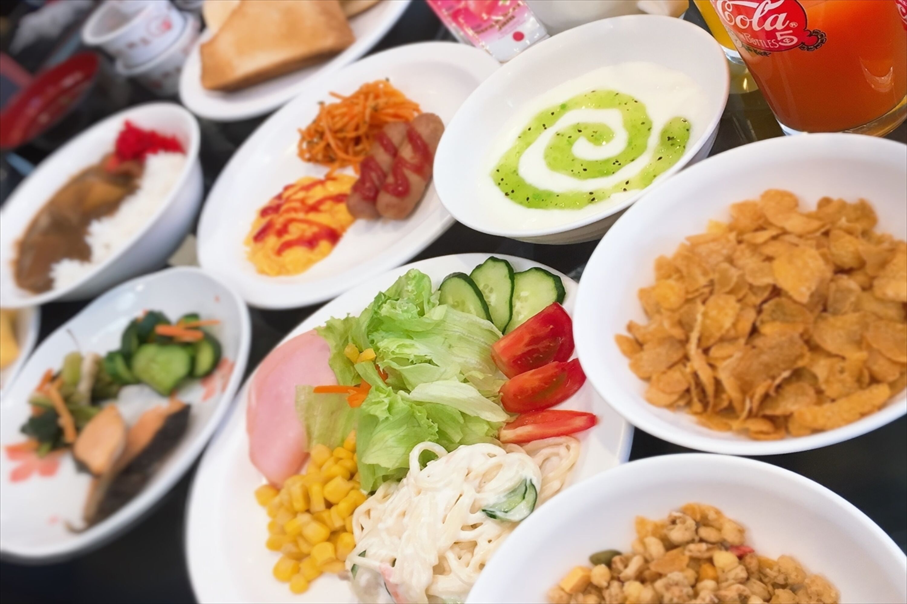 Une table où l’on trouve divers plats, notamment des salades, des nouilles et un bol de céréales.