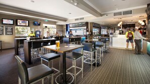 A modern bar area with high stools, a counter with a menu display, and a seating area with tables and chairs. - Granville Hotel (Granville)