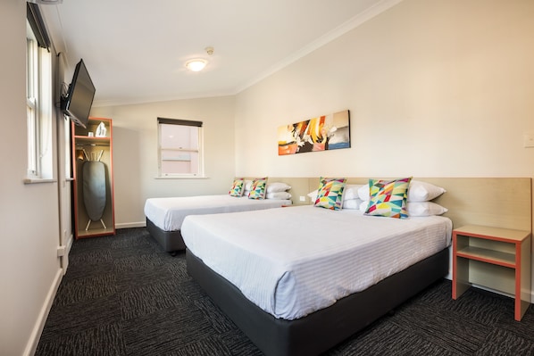 A hotel room with two beds, a flat-screen TV, a painting, and a small table. - Granville Hotel (Granville)