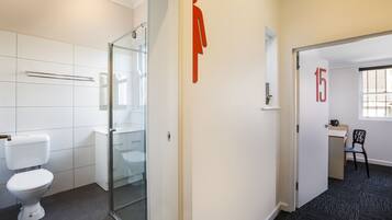 A modern bathroom with a toilet, glass shower enclosure, and a visible number '15' on the wall.