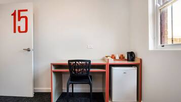 Una habitación con escritorio, silla y refrigerador.