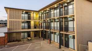Un hotel de varios pisos con balcones numerados y una zona de estar exterior cubierta.