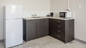 Una cocina con un refrigerador blanco, un microondas en la encimera y armarios de madera oscura.