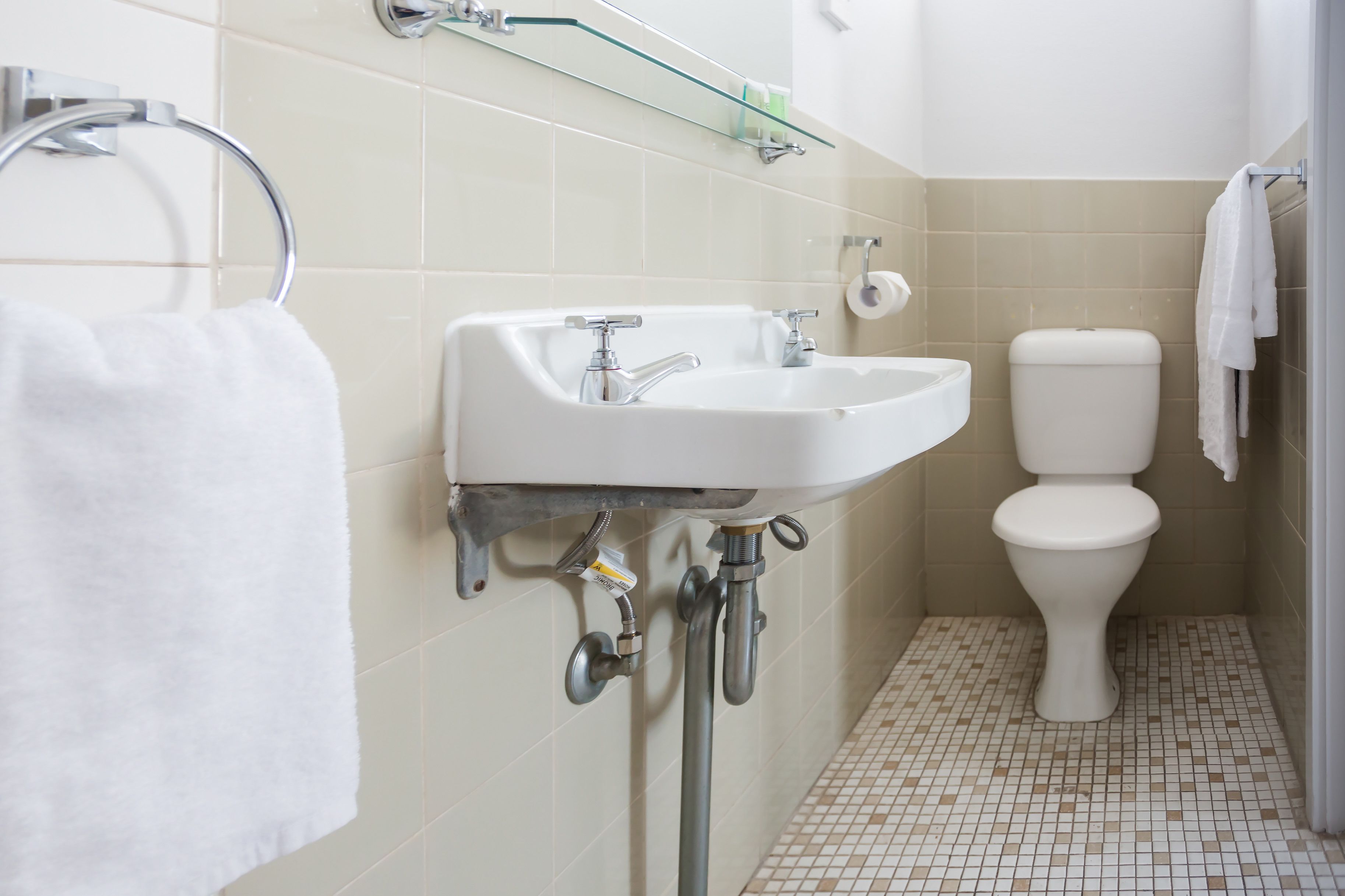 Casa de banho com lavatório branco, sanita e chão em azulejos.