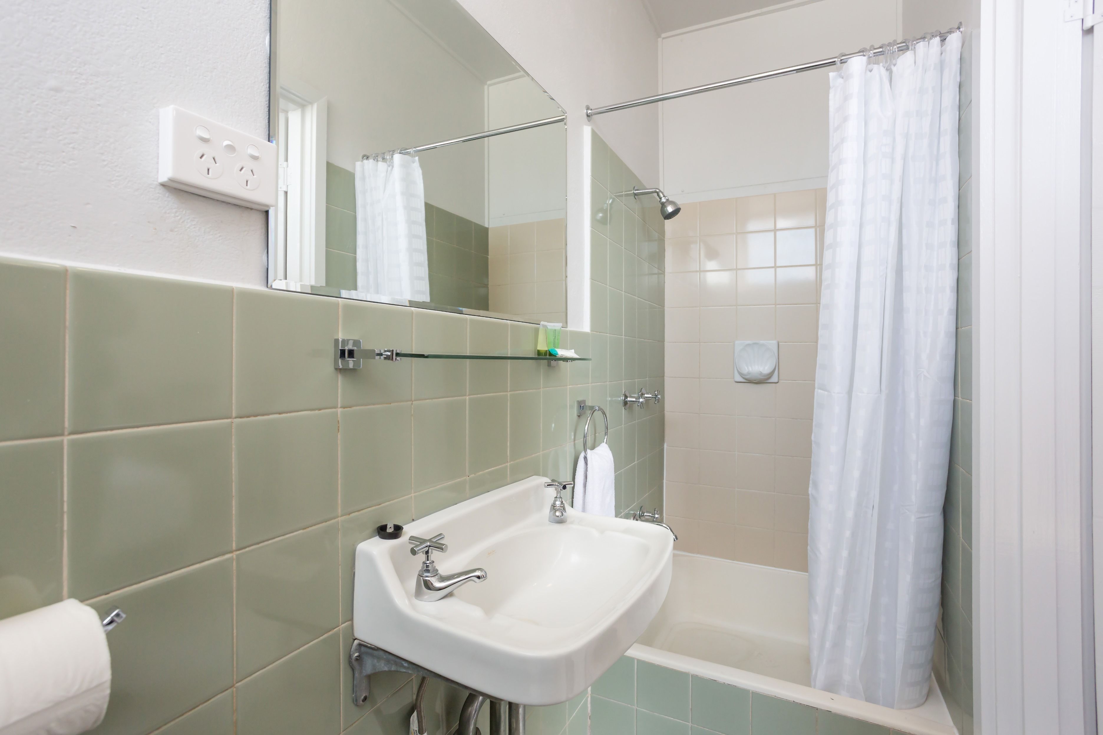 Un baño con lavamanos, espejo y ducha.