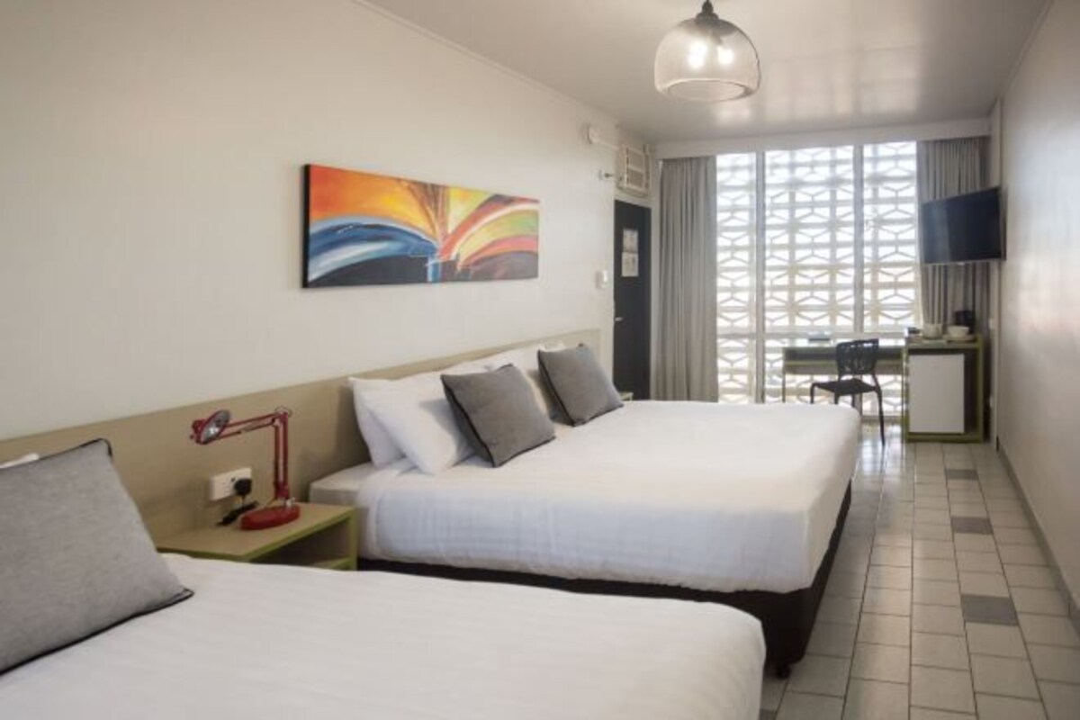 A hotel room with two beds, a desk, a TV, and a window with a view.