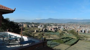 Eine Terrasse mit Sitzgelegenheiten und Blick auf eine Stadtlandschaft mit Bergen im Hintergrund.