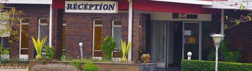 Un área de recepción con letrero, paredes de ladrillo y plantas en macetas.