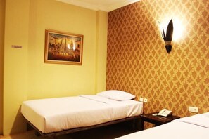 Ein Einzelbett mit weißer Bettdecke in einem Zimmer mit gelben Wänden und gemustertem Wandpapier. Ein Bild hängt an der Wand, und eine Wandleuchte ist angebracht.