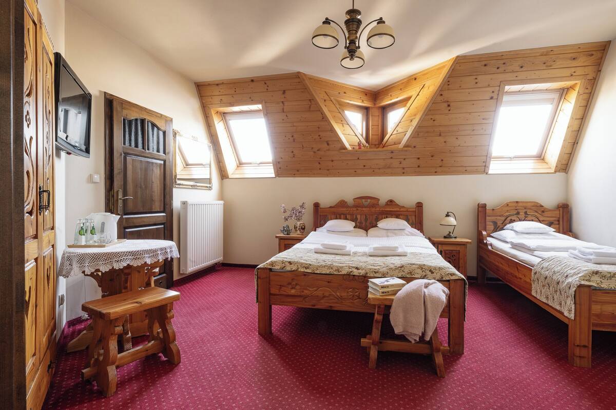 A bedroom with two wooden beds, a wooden desk, and a red carpet.