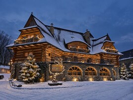 Un hotel de estilo cabaña de troncos con varios balcones, fachada de piedra y un paisaje nevado.