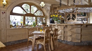 Un interior rústico de madera con una zona de bar, sillas de madera y plantas en macetas.