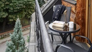 Un balcón con una pequeña mesa, una silla, un libro, una taza y una chaqueta colgada de la barandilla.
