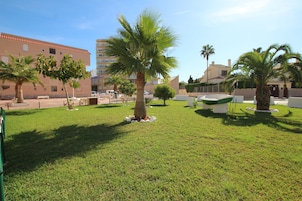 Un área verde bien cuidada con palmeras y una estructura circular blanca, rodeada de edificios.