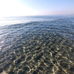 A clear view of a beach with shallow water revealing the sandy bottom. - Apartamentos Tesy (Cartagena)
